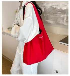 Detailed side view of the red nylon tote bag featuring white letter printing and large capacity
