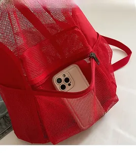 Detail shot of the red mesh backpack front zipper pocket with a phone for size reference