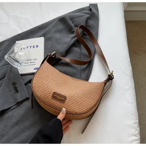 Détail d'un sac bandoulière en croissant tissé marron avec bandoulière en cuir
