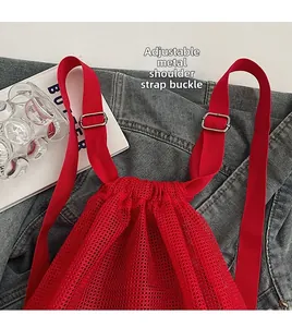 Detail of red mesh drawstring bag with adjustable metal buckle on shoulder strap