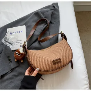 Détail du sac croissant tissé avec bordure en cuir et peluche sur une veste grise chic