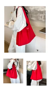 Red oversized nylon tote bag with white letter print shown on shoulder for daily commute