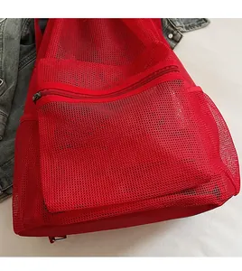 Detail of red mesh drawstring backpack featuring breathable fabric and zipper pocket