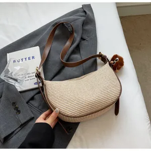 Détail du sac demi-lune tissé avec garniture en cuir marron et breloque peluche