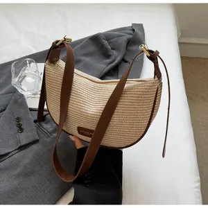 Détail du sac demi-lune tressé beige avec bandoulière en cuir marron et boucle
