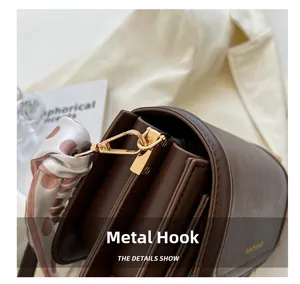 Detail view of premium gold hardware hook and polka dot scarf on dark brown leather bag