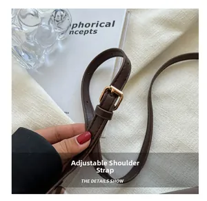 Detail of dark brown leather adjustable shoulder strap with gold metal buckle