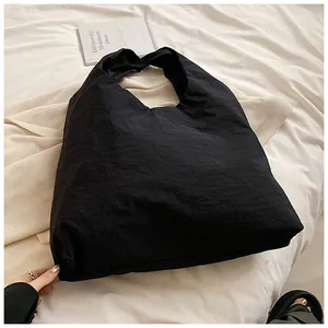 Detailed texture view of a black large capacity nylon tote bag on a cozy bed background