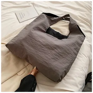 Detail of grey nylon tote bag with unique crinkle texture and white printed logo