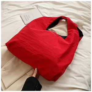 Close-up of a large red nylon tote bag with textured fabric on a white background