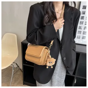 Detailed view of light brown leather crossbody bag with triple-layer structure and bear charm