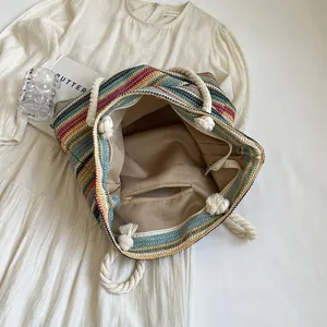 Colorful woven straw tote bag with striped pattern and white rope handles for summer beach