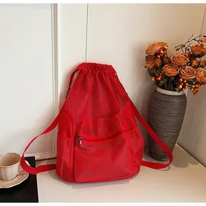 Close-up of red mesh drawstring backpack with zipper pocket on a minimalist table