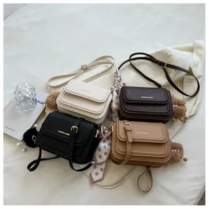Detail of four colorful PU leather crossbody bags with scarves and plush charms