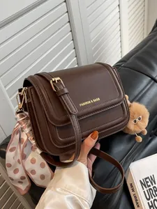 Minimalist dark brown leather crossbody bag with scarf detail and plush charm decoration