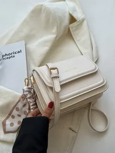 Elegant cream crossbody bag with grooved texture and polka dot scarf detail