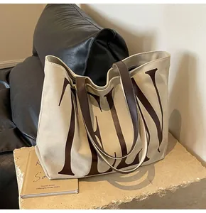 Détail du sac cabas en toile avec anses en cuir sur pierre pour un style décontracté