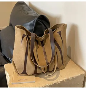 Détail du grand sac cabas en daim marron avec imprimés lettres et anses en cuir