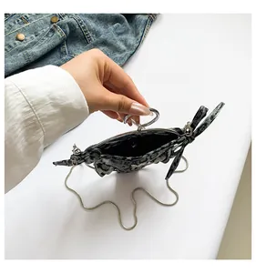 Gros plan d'un mini sac à texture marbre avec poignée argentée et chaîne en métal