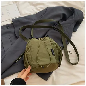Detail of army green nylon bucket bag with mesh pocket and drawstring closure