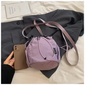 Detail view of small lilac nylon bucket bag with mesh side pocket and logo tag