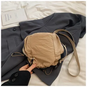 Detail of khaki nylon bucket bag with mesh side panels and adjustable shoulder strap