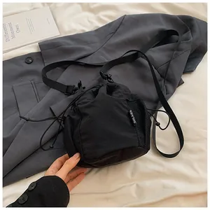 Detail of black nylon drawstring bucket bag with mesh side pocket and logo patch