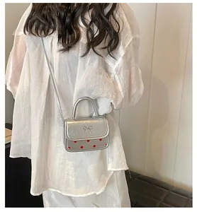 Silver patent leather crossbody bag with metallic bow and red polka dot detail