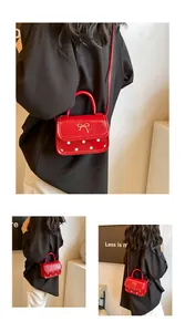 Detail of red patent leather crossbody bag with white polka dots and golden bow accent