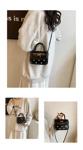 Detail of a mini black crossbody bag with white polka dots and a silver bow clasp