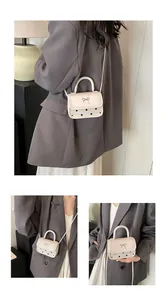 Detail view of mini cream crossbody bag with gold bow clasp and black polka dots