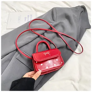 Close-up of mini red polka dot crossbody bag with silver bow detail on gray suit