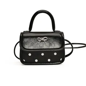 Polka dot mini crossbody bag with silver bow accent and glossy leather texture