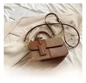 Close-up of brown textured patchwork handbag with leather handle and fashion tag
