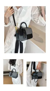 Detail of grey textured fabric and black leather stitching with gold hardware on handbag