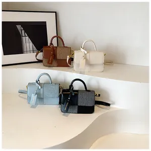 Detail of four textured patchwork crossbody handbags on a display stand in various colors
