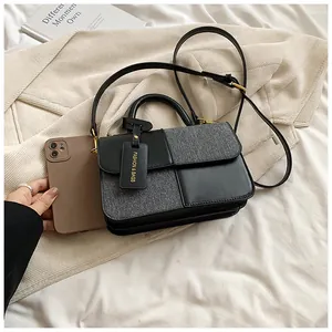 Detail of contrast stitch handbag featuring black and grey textures and golden hardware