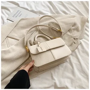 Detail of off-white patchwork crossbody bag with gold hardware on aesthetic background