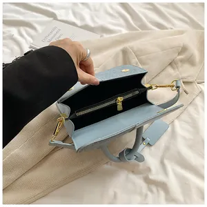 Top view of light blue denim handbag interior with zipper pocket and golden hardware