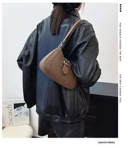 Sac porté épaule en cuir marron avec boucle argentée sur une veste en cuir noir