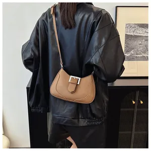 Détail du cuir marron à motif litchi et de la boucle en métal argenté sur le sac croissant