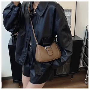 Détail du sac sous le bras en cuir grainé marron avec boucle métallique argentée chic