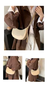 Détail du sac demi-lune beige avec bandoulière à boucle réglable et lettrage de mode