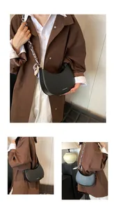 Détail du sac croissant noir avec bandoulière chaîne en métal et foulard en soie