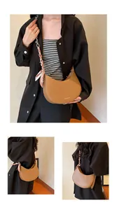 Détail du sac demi-lune marron avec bandoulière en foulard de soie et logo en métal doré