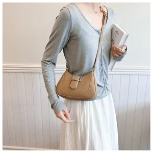 Vue détaillée du sac selle camel avec boucle argentée porté par un mannequin