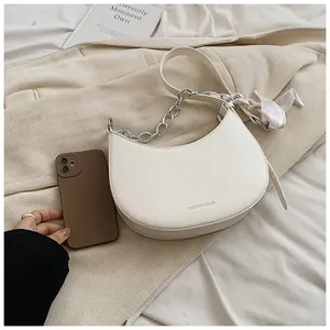 Détail du sac demi-lune blanc avec chaîne argentée et foulard en soie décoratif