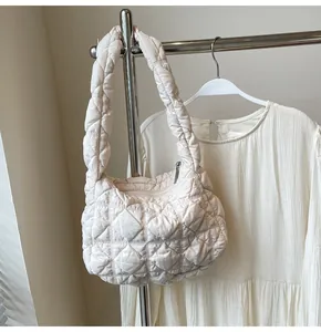 Détail du sac à main matelassé crème avec coutures en losange et poignée rembourrée