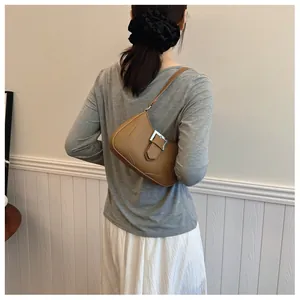 Détail de la boucle en métal argenté sur le sac sous le bras en cuir grainé marron
