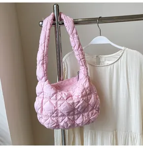 Détail d'un sac nuage matelassé rose suspendu à côté d'une robe blanche élégante